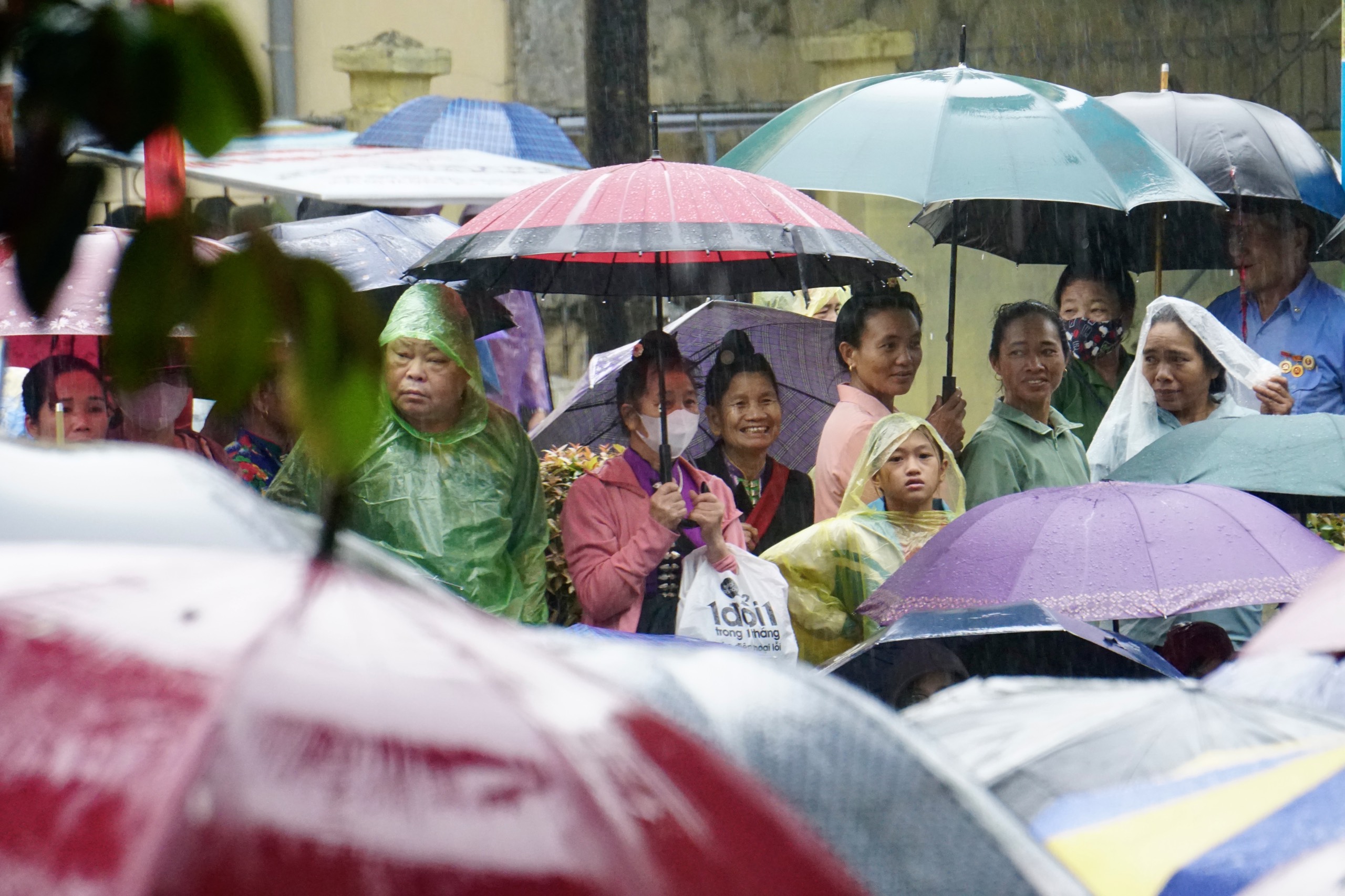 People stands in the rain to watch the military march and parade on the streets of Dien Bien Phu