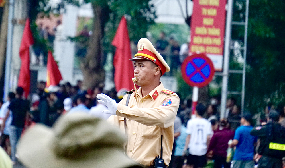 People stands in the rain to watch the military march and parade on the streets of Dien Bien Phu